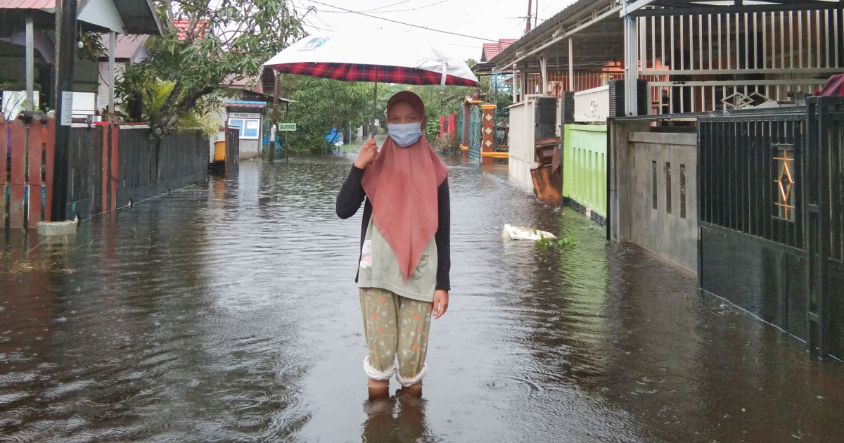 woman holding umbrella in flooded street for world health day