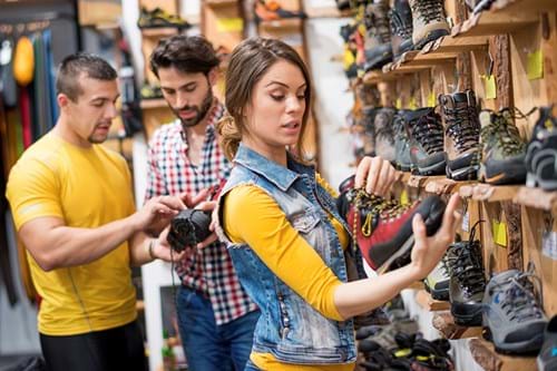 Female shopper comparing hiking shoes in a retail store
