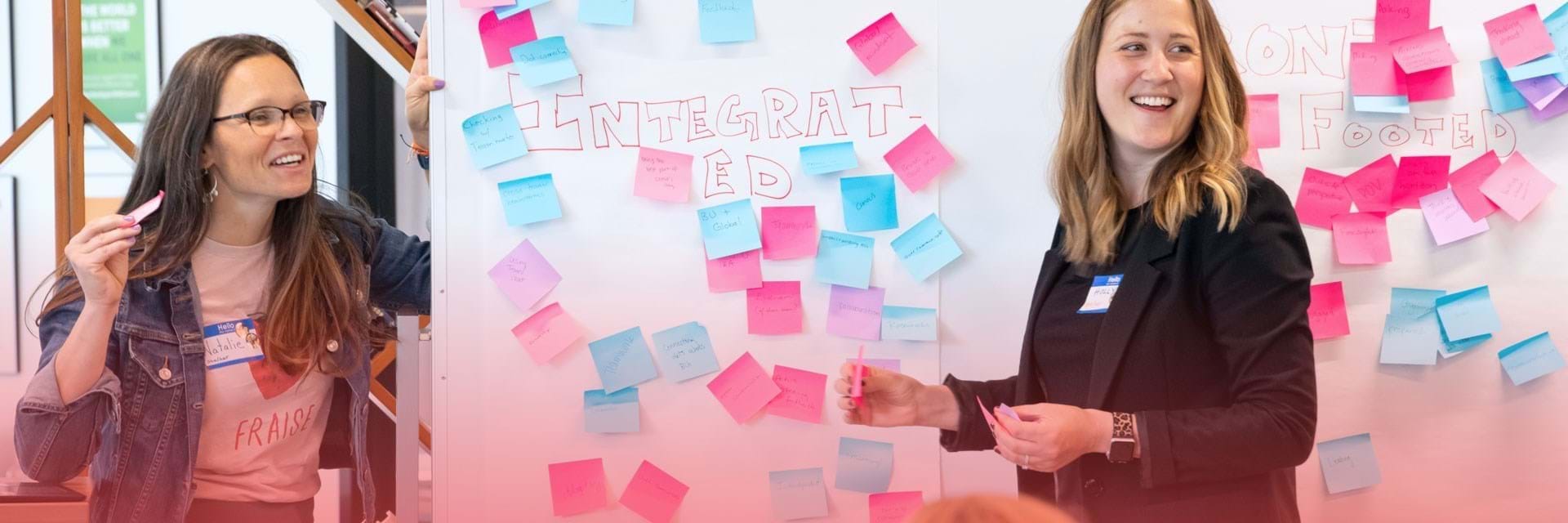 Two women brainstorming with sticky notes on a board