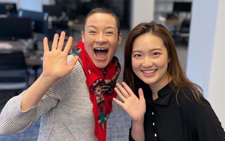 Two employees waving in the office